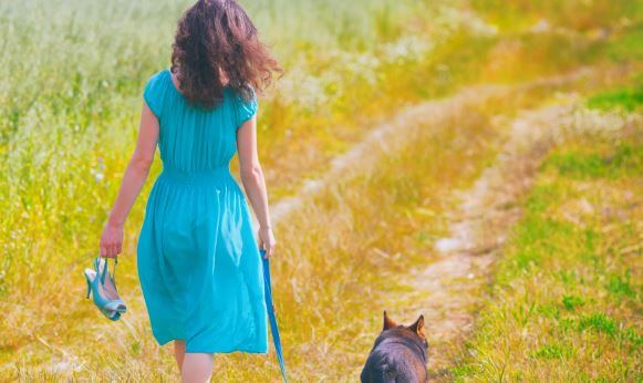 Mujer caminando por el campo con su perro