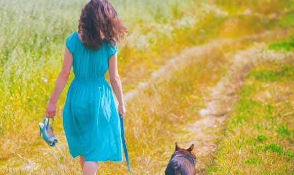 Mujer caminando por el campo con su perro