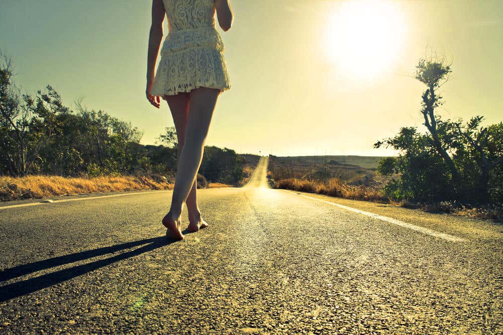 Mujer caminando descalza por la carretera