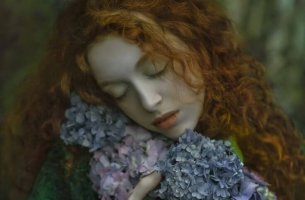 Mujer con los ojos cerrados con la cabeza apoyada en flores