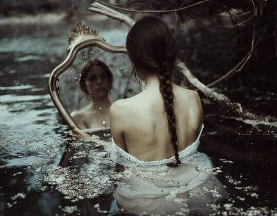 Mujer triste mirándose en un espejo