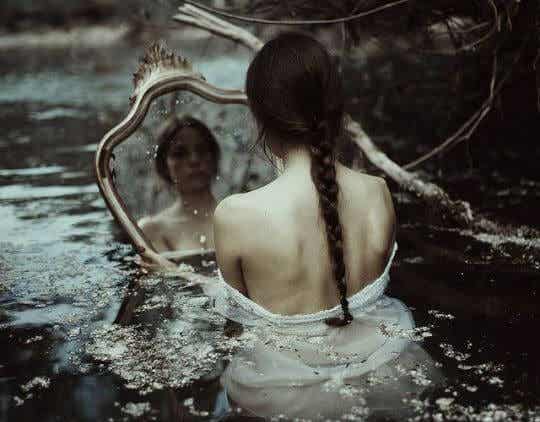 sad woman looking in the mirror in cold water.