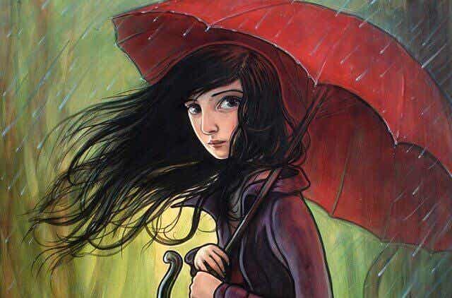 Ragazza con un ombrello rosso mentre piove.