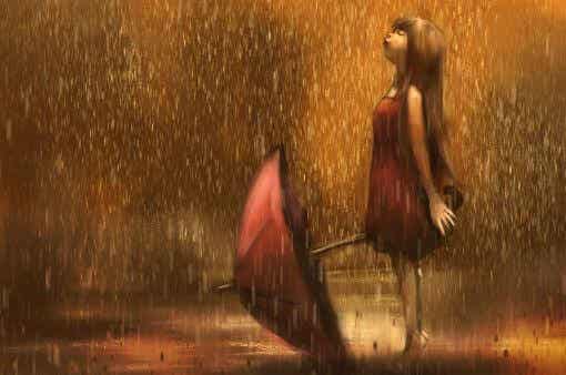 Chica sonriendo bajo la lluvia tras alcanzar la libertad emocional