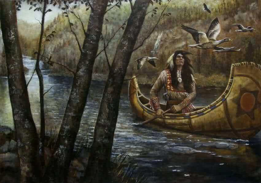Indio navegando por el río con una canoa