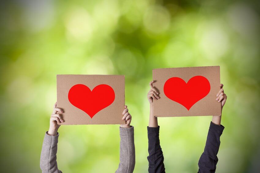 Manos sujetando carteles con corazones