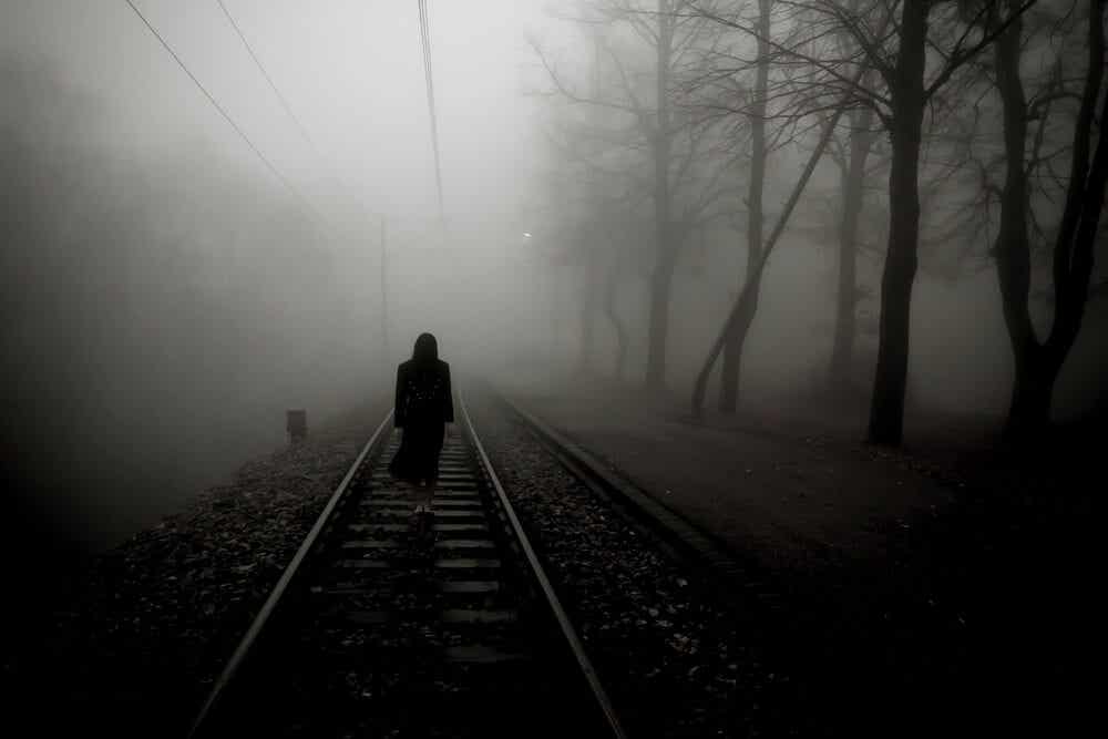 Mujer caminando por las vías del tren