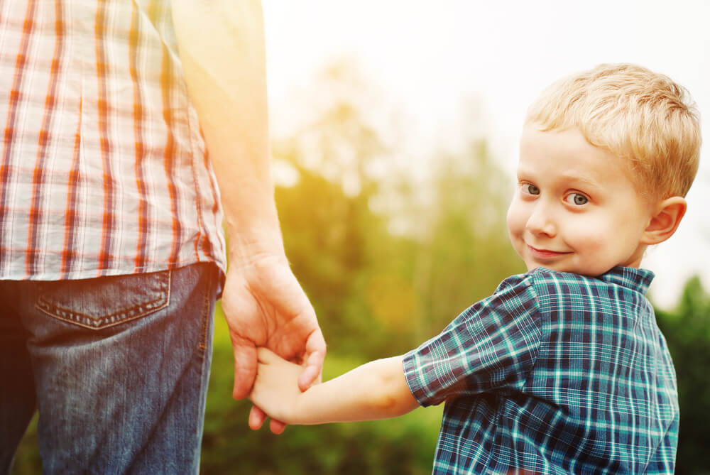 Niño cogiendo la mano de su padre y sonriendo