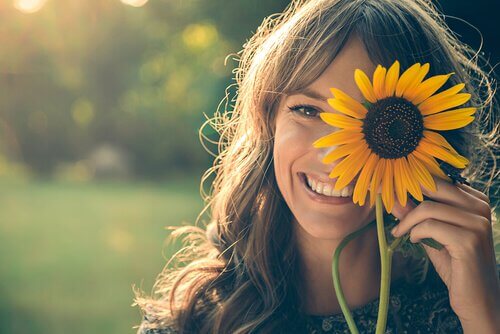 Mujer con un girasol sonriendo con felicidad