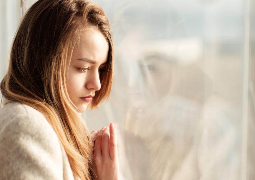 Mujer triste mirando por la ventana