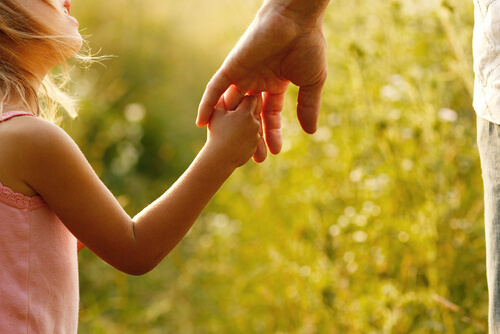 Niña agarrando mano a su padre