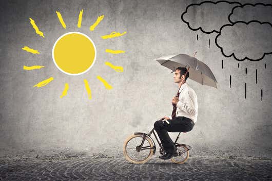Uomo in bicicletta con ombrellone al sole.