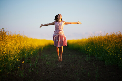 Mujer feliz con los brazos abiertos por el campo