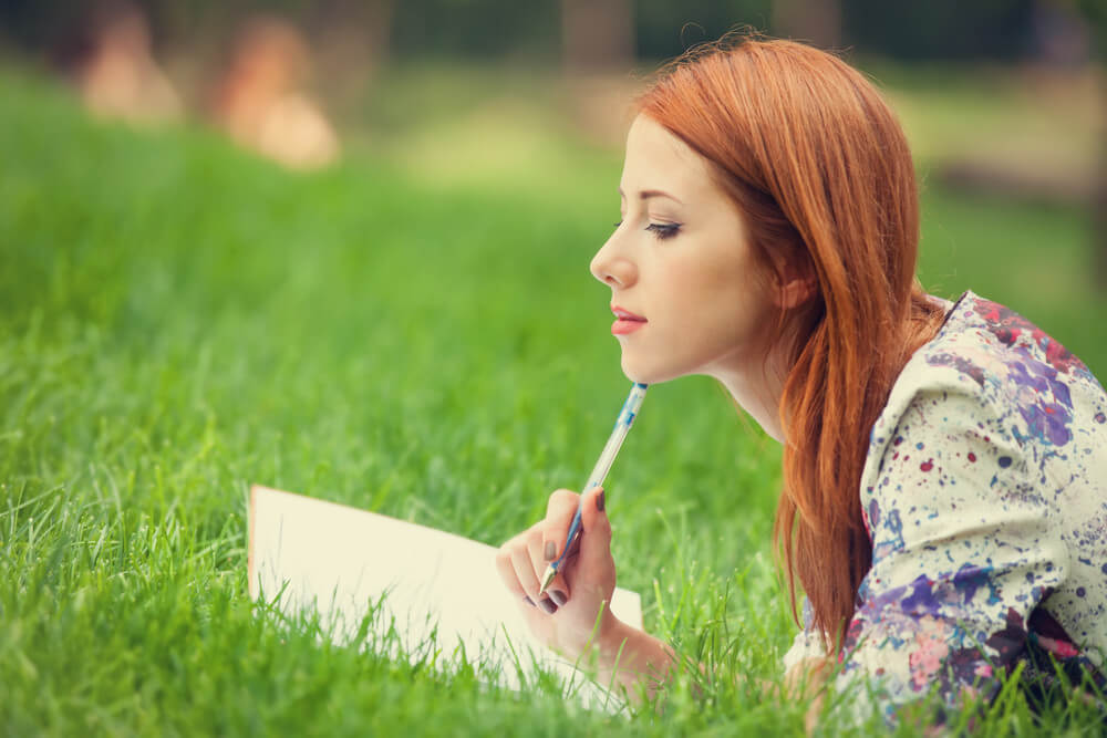Mujer sobre el césped escribiendo