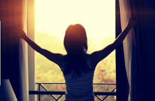 Mujer abriendo la ventana cuando sale el sol