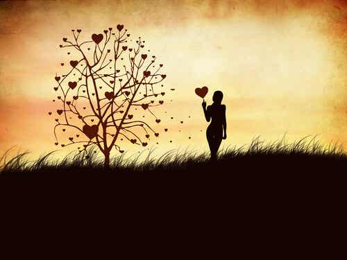 Mujer con globo de corazón en la mano junto al árbol de los sentimientos