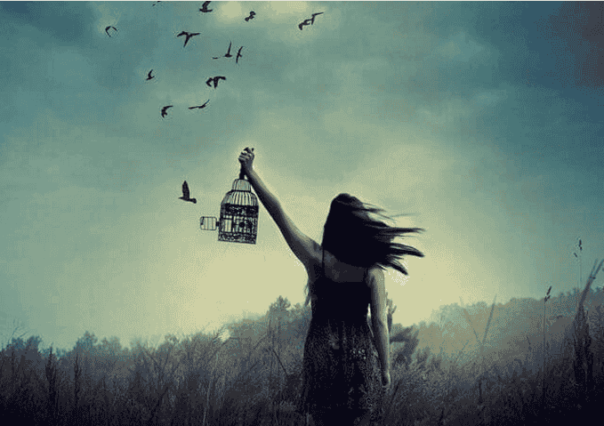 Mujer con jaula liberando pájaros