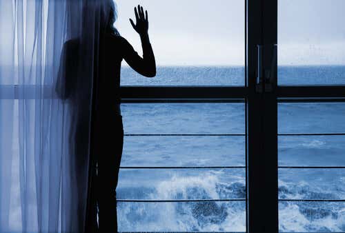 Mujer preocupada mirando por la ventana el mar
