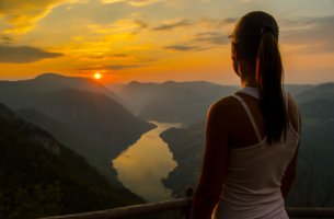 Mujer observando el atardecer desde la montaña