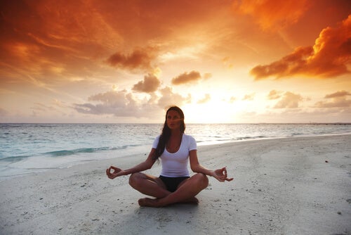Mujer en posición de loto en la playa haciendo meditación