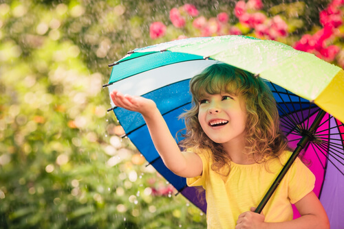 Niña feliz sonriendo con paraguas de colores