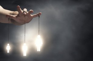 Mano manipulando marionetas representando el perfil psicológico de un maltratador