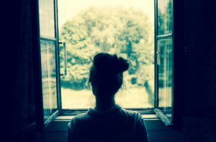 Mujer mirando por la ventana y recordando