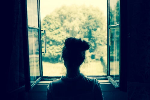 Mujer mirando por la ventana y recordando