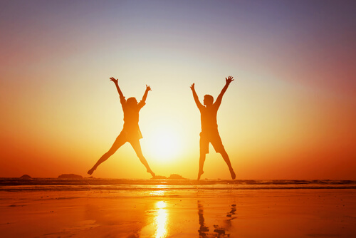 Pareja feliz saltando en la playa