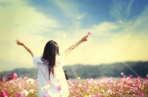 Mujer con una flor en la mano mirando al infinito