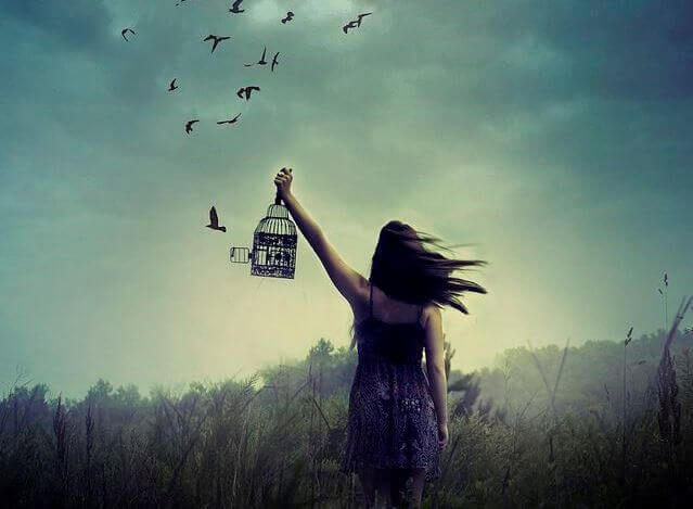 Donna che lascia liberi gli uccelli nella loro gabbia.