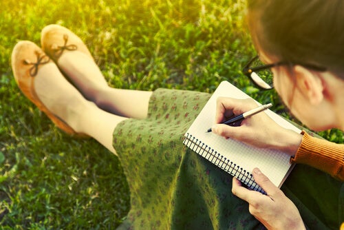 Chica escribiendo en una libreta en el campo