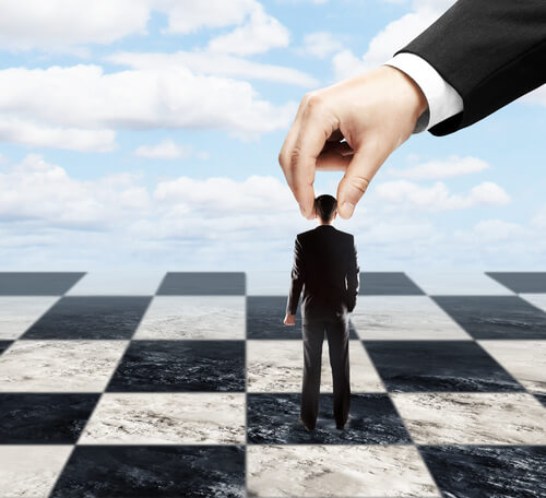 Hombres sufriendo la manipulación de otro como si fuera un peón de ajedrez