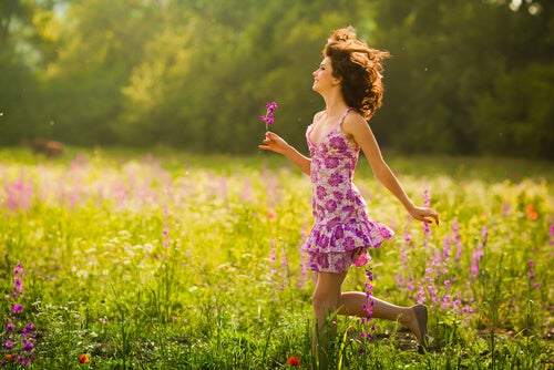 Mujer caminando entre flores sonriendo y feliz
