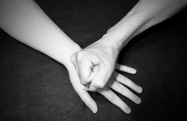 Un puño sobre una mano como símbolo de violencia de género