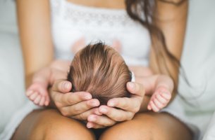 Mujer sujetando la cabeza de su hijo simbolizando postparto