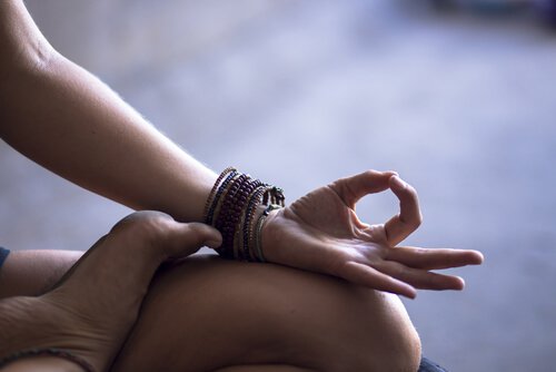 Brazo sobre pierna de una mujer meditando