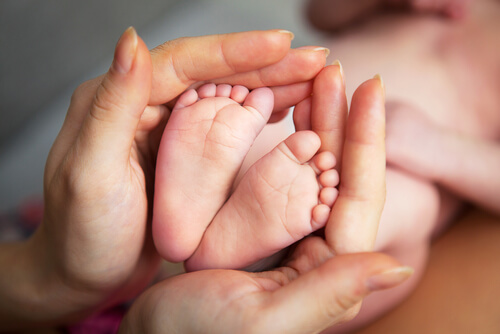 Mother's hands surrounding her son's feet