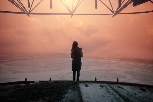 Mujer mirando al horizonte al atardecer