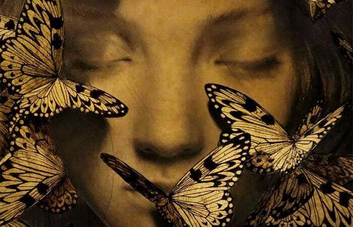 Mujer con los ojos cerrados rodeada de mariposas