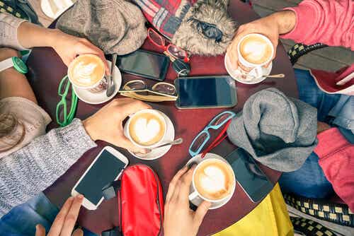 Grupo de amigos tomando café con móviles encima de la mesa