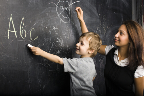 Maestra con niño en la pizarra dibujando