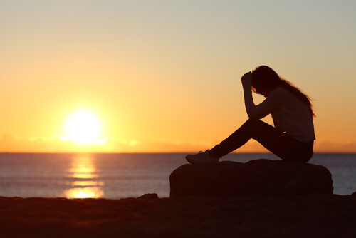 Mujer con dolor sentada al atardecer