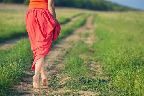 Mujer con falda roja andando por un camino