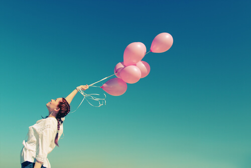 Mujer sujetando globos rosa