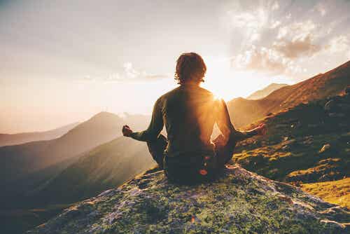 Mann uten høydeskrekk som mediterer på fjellet
