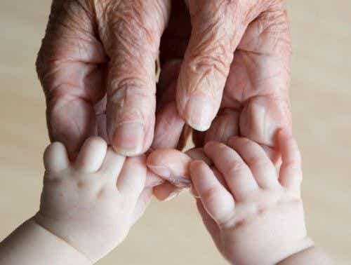 manos de un anciano cogiendo las de un bebé