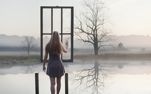 mujer ante una ventana suspendida en el aire representando la comunicación asertiva