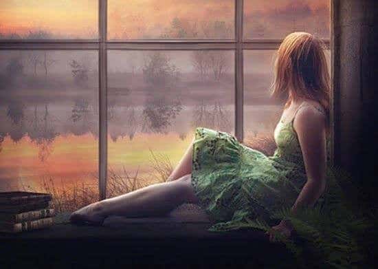 Mulher de vestido verde sentada diante de uma janela