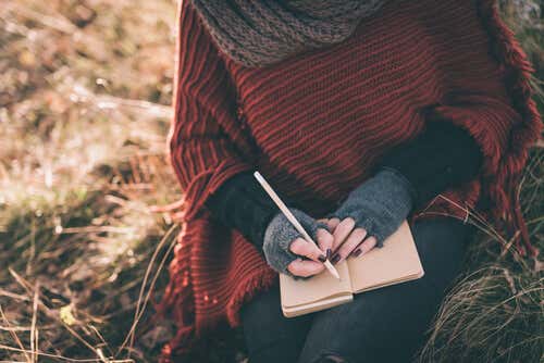 Woman's hands writing in a notebook in the field